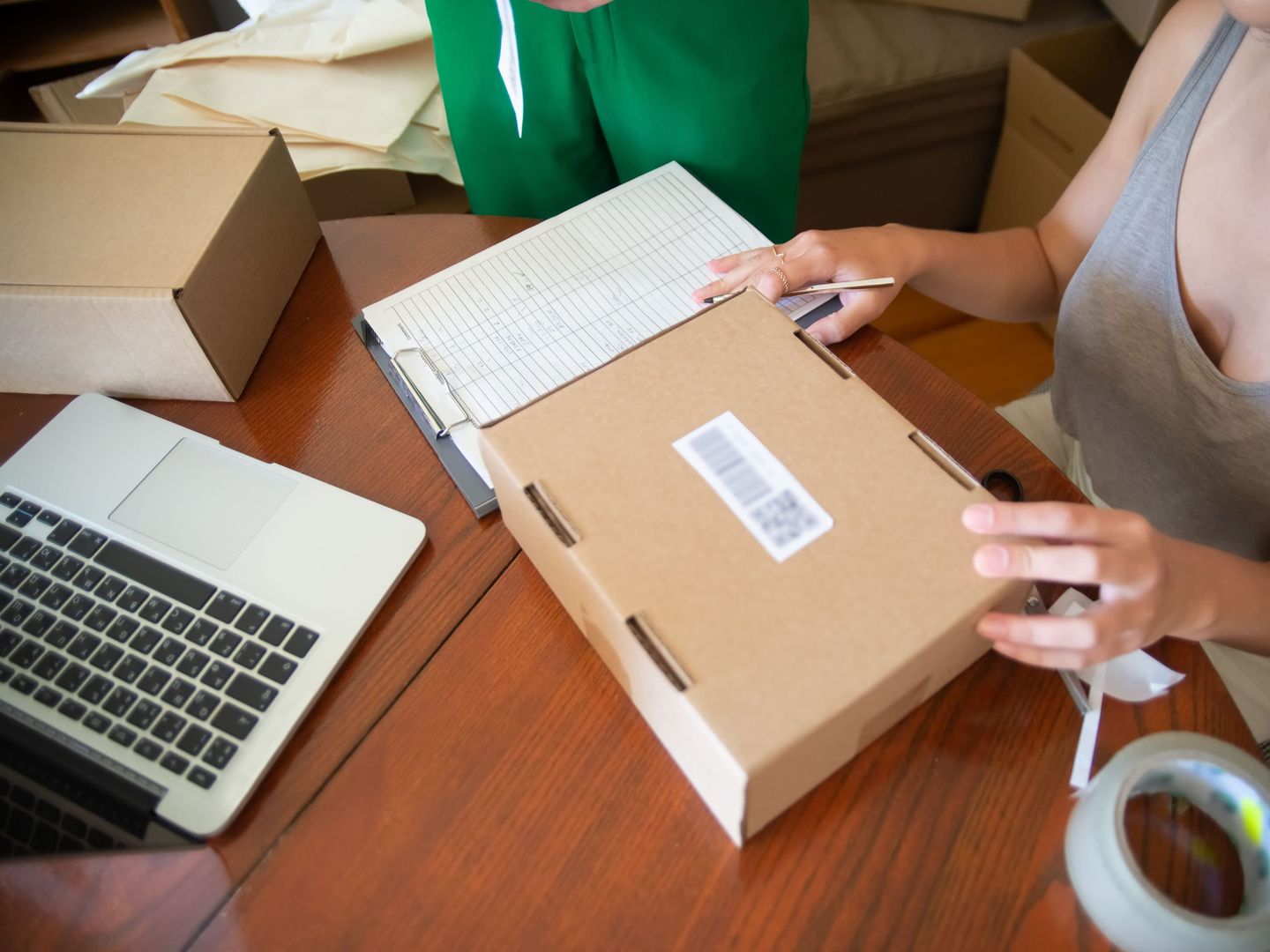 An online seller packing orders beside a laptop